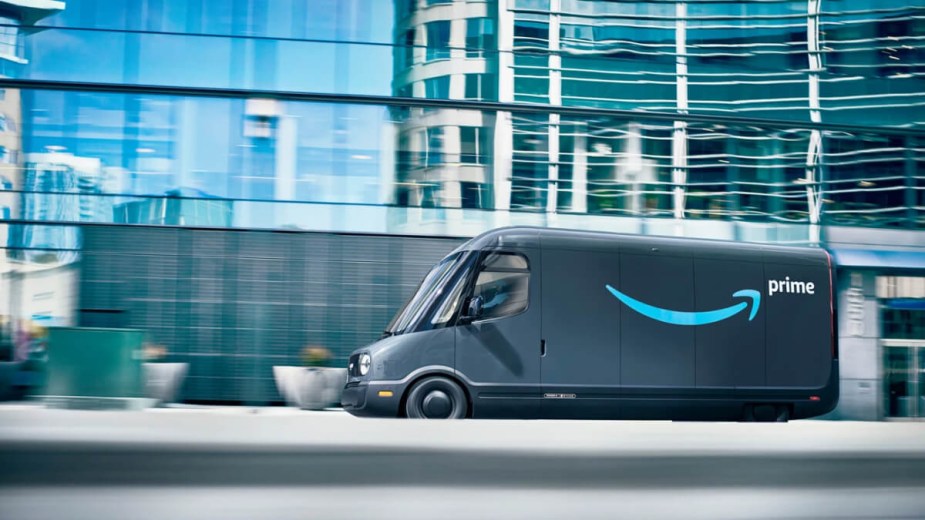 An electric Amazon delivery truck by Rivian drives in a city.