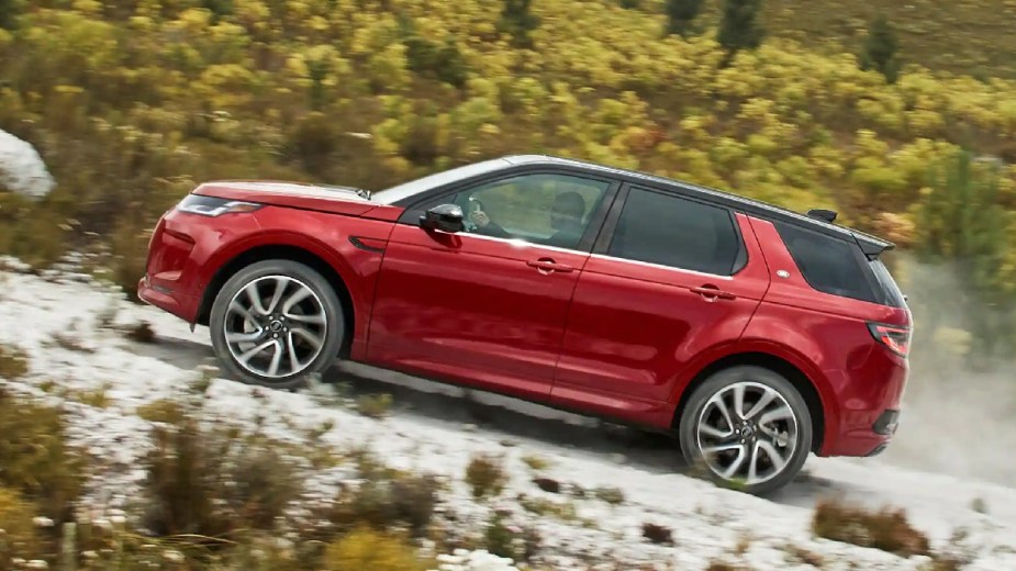Side view of red 2023 Land Rover Discovery Sport, most affordable new Land Rover and an off-road luxury SUV bargain