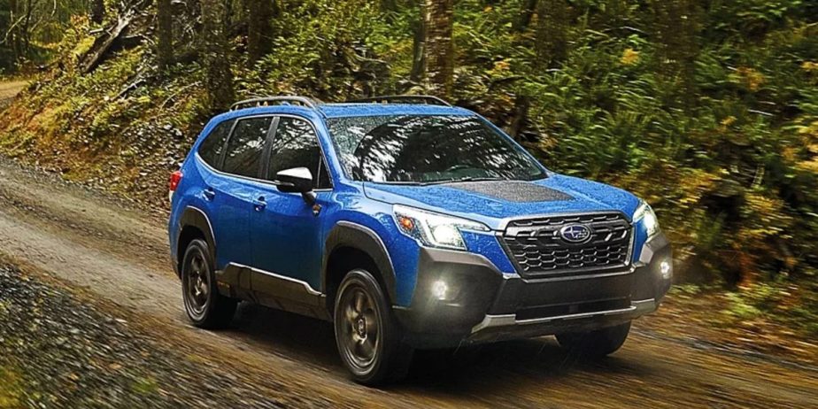 A blue 2023 Subaru Forester small SUV is driving off-road. 