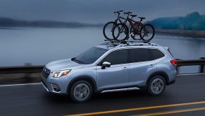 A blue Subaru Forester small SUV is driving on the road.