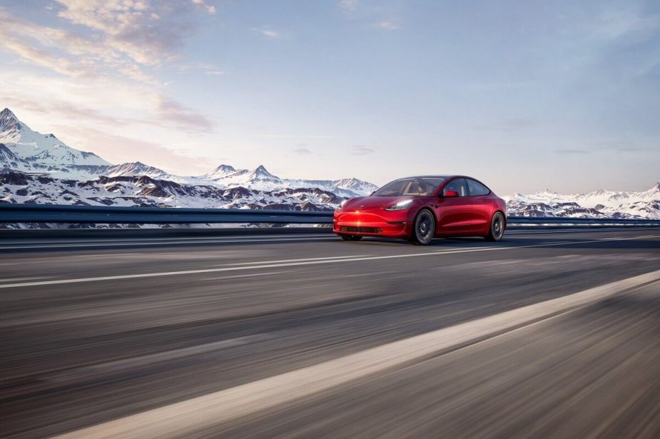 A red Tesla Model 3 Performance blasts down a mountain road in the snow. 