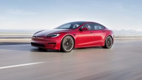 A red 2023 Tesla Model S luxury electric car blasts down a desert road.