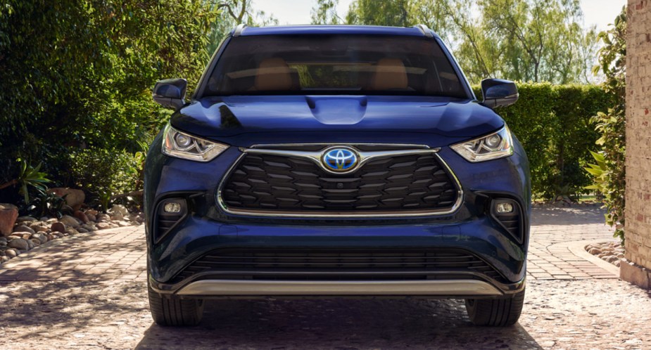 A blue 2023 Toyota Highlander Hybrid midsize hybrid SUV is parked outside.