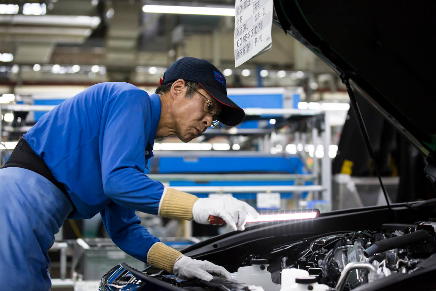 A Toyota factory worker inspects a vehicle to ensure the company's legendary reliability.