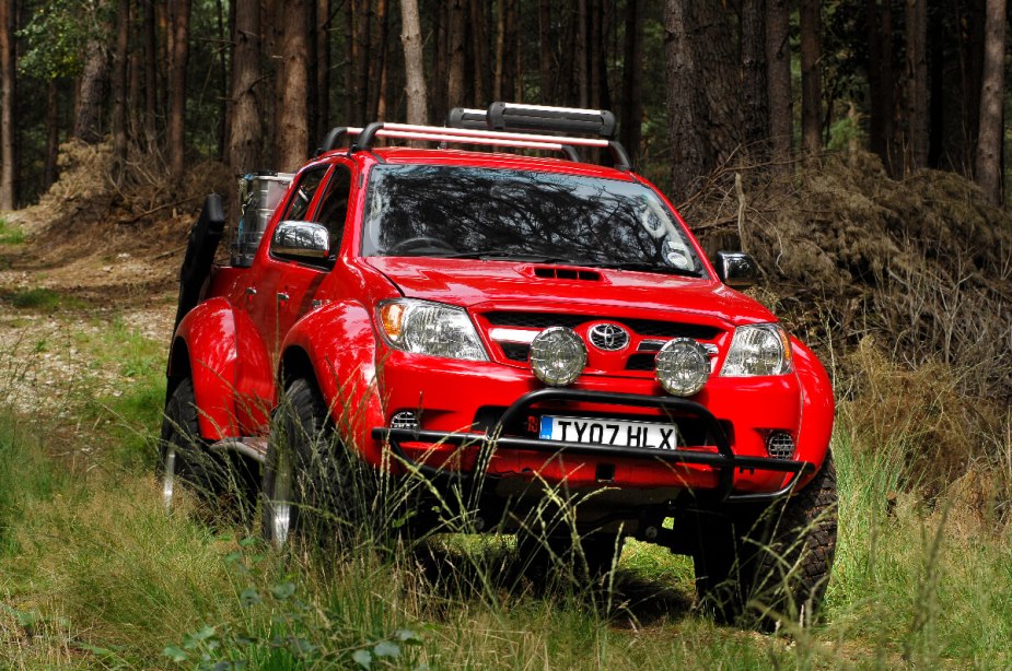 A red Toyota truck is driving, is the Hilux illegal in America?