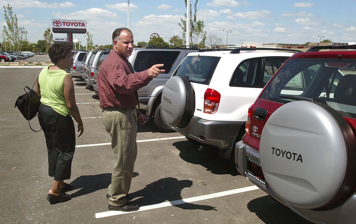 A car salesmen helping a customer pick out a used Toyota RAV4. They'll want to avoid the worst Toyota RAV4 model years.