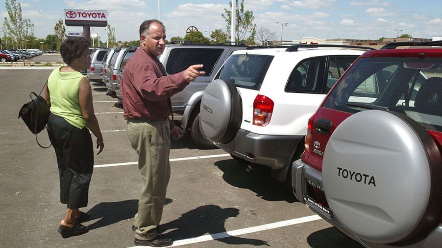 A car salesmen helping a customer pick out a used Toyota RAV4. They'll want to avoid the worst Toyota RAV4 model years.