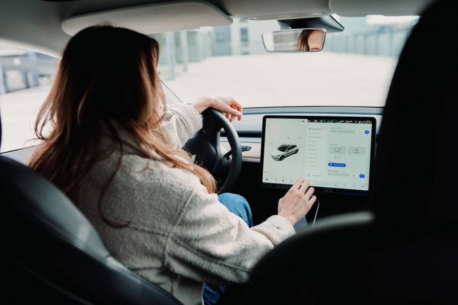 A woman interacting with the touchscreen on her Tesla, may pay more for car insurance based on her gender.