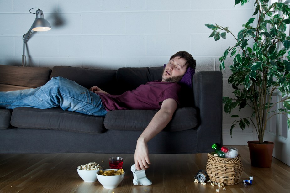 A young man asleep on a sofa.