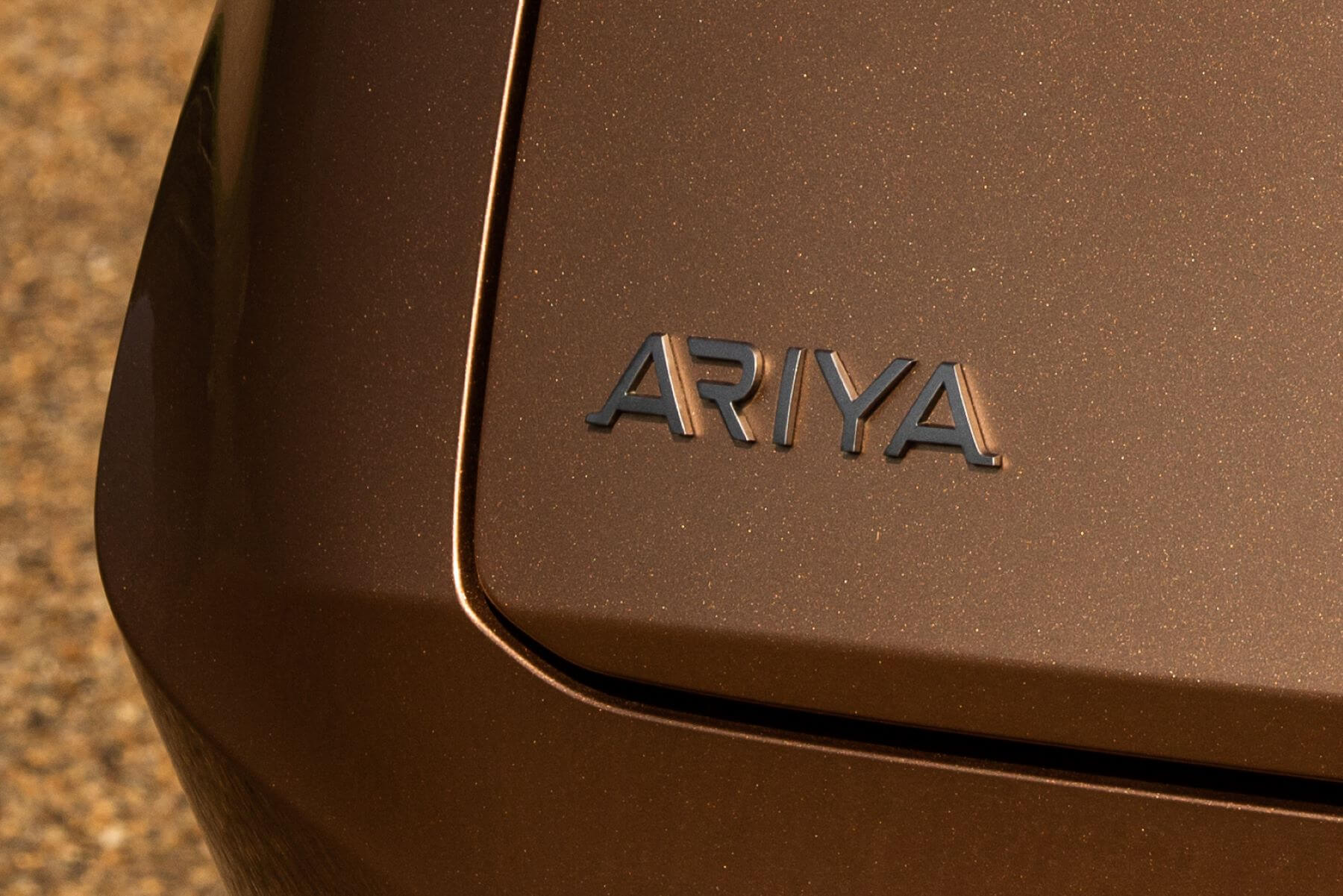 Rear Ariya model badging on the trunk of a bronze 2023 Nissan Airya all-electric (EV) compact SUV model