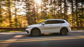 An Oryx White 2023 Volkswagen Tiguan SEL R-Line compact SUV driving on a forest highway