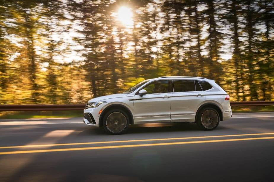 An Oryx White 2023 Volkswagen Tiguan SEL R-Line compact SUV driving on a forest highway