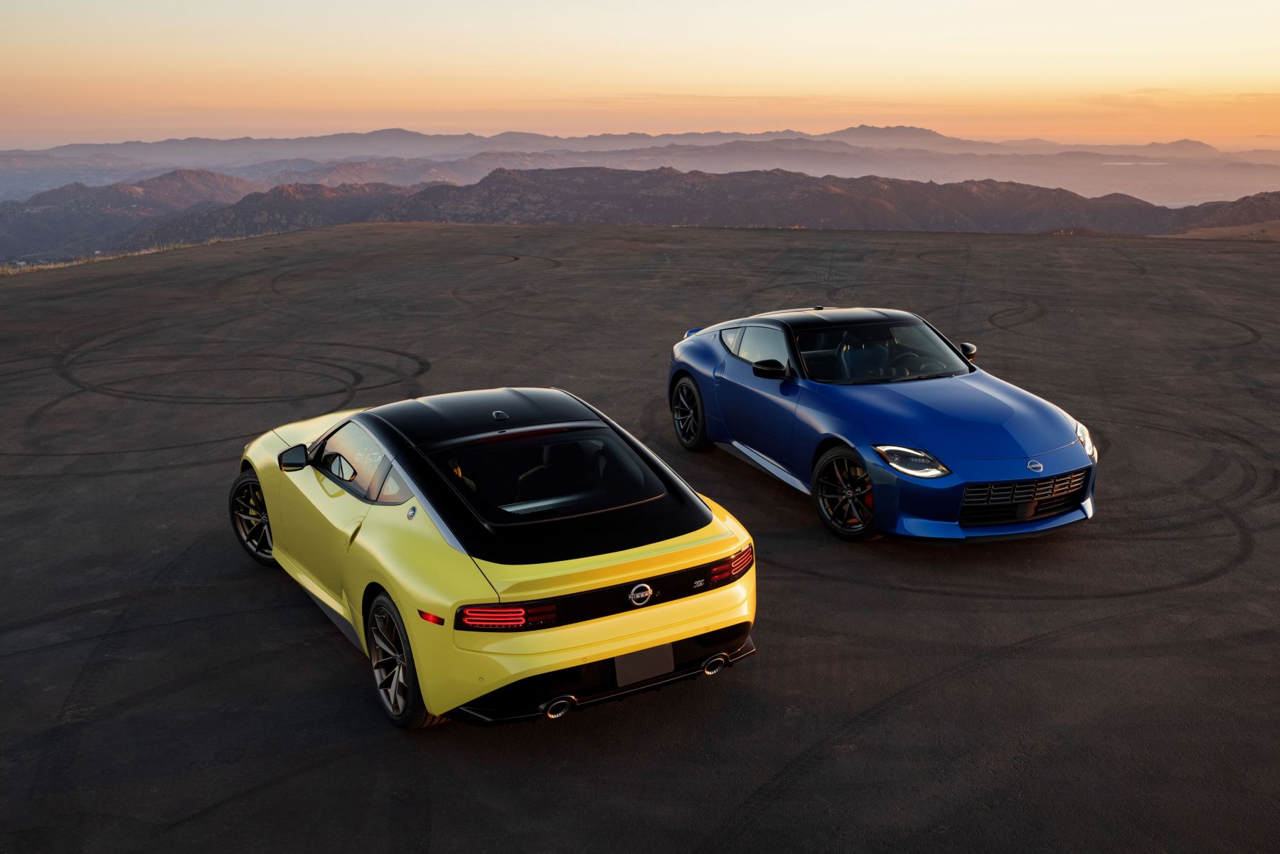 An overhead shot of yellow and blue 2023 Nissan Z sports car models with a sunset in the background