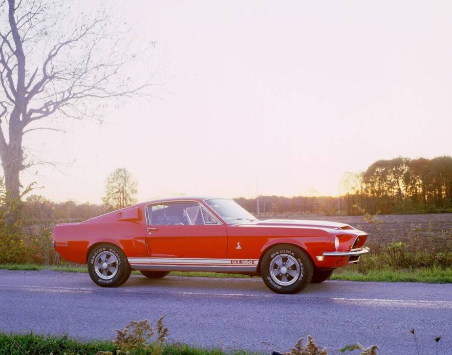 A bright red 1968 Ford Mustang Shelby GT350 shows off its muscle car styling in the sunlight. 