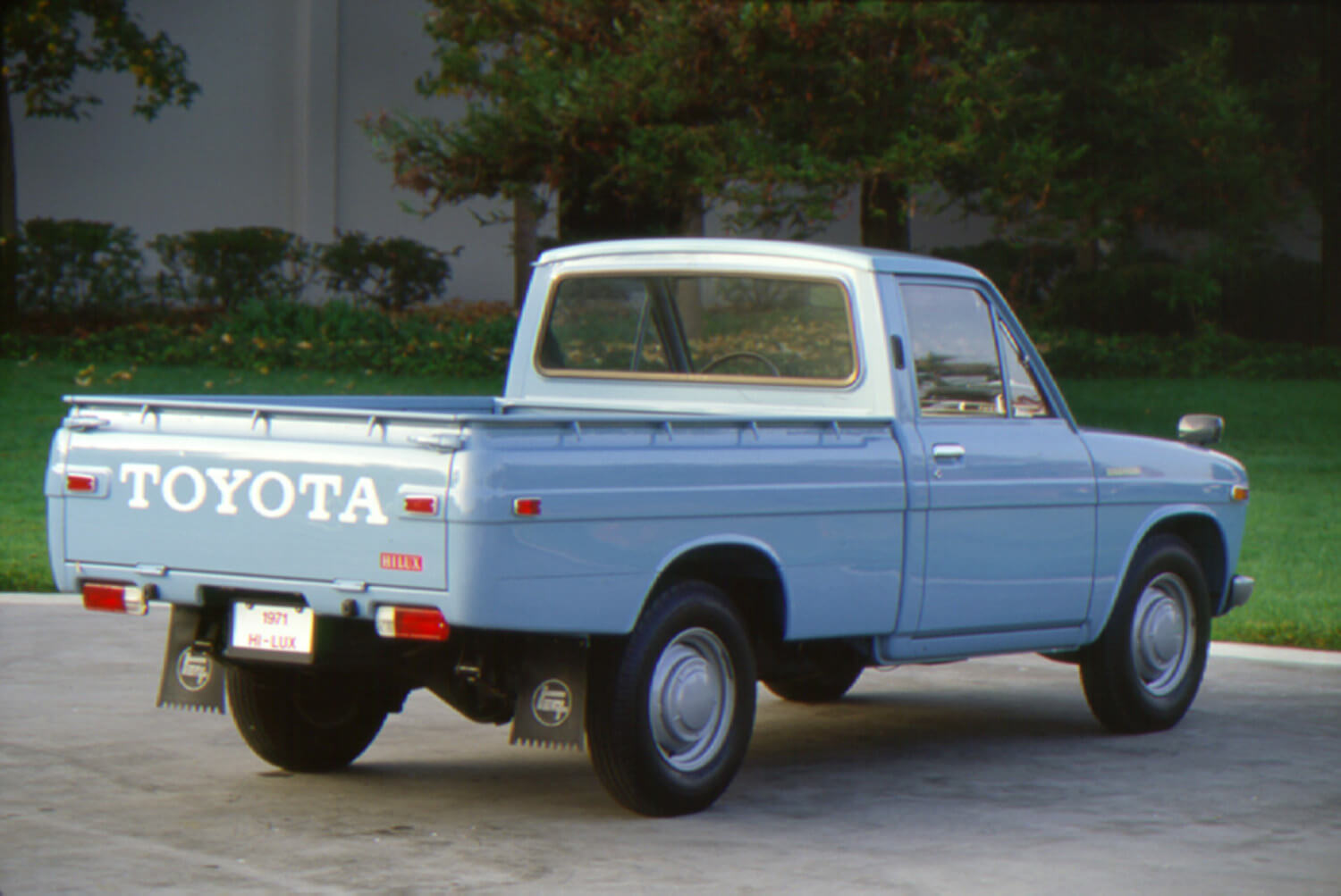 The tailgate and bed of a blue Toyota hi-lux pickup truck, trees visible in the background.