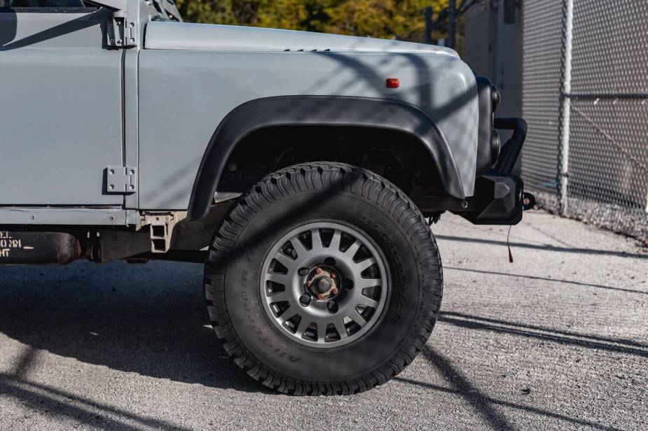 Closeup of the front rim and tire of a Land Rover Defender 6x6 truck.