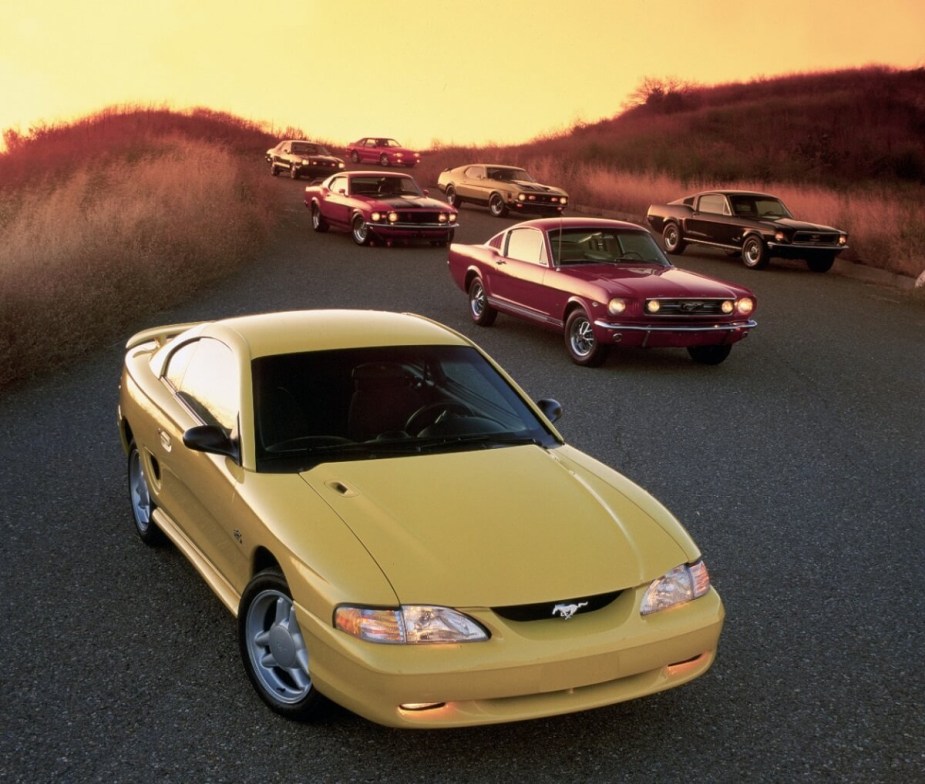 An SN95 Mustang poses with a series of first-gen Mustangs. 