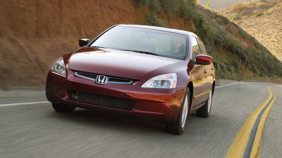 A red 2003 Honda Accord model cruises on a desert road.