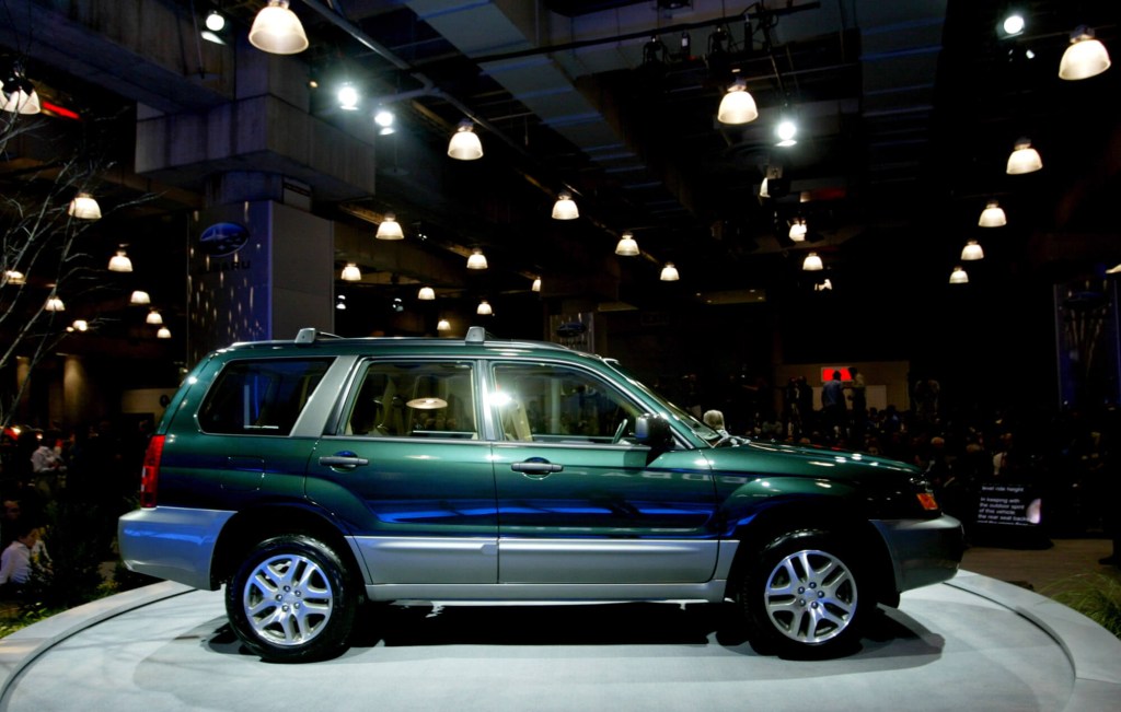 A green 2004 Subaru Outback on display at an auto show. 