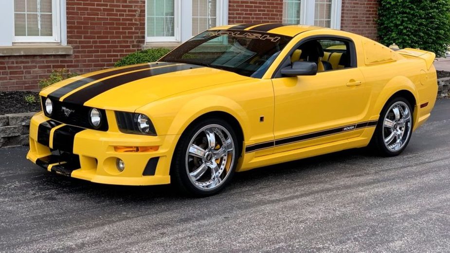 Yellow 2005 Ford Mustang GT parked and posed in front of a brick building