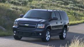 A black 2007 Chevy Suburban, which is one of the worst Chevy Suburban model years, driving outdoors.