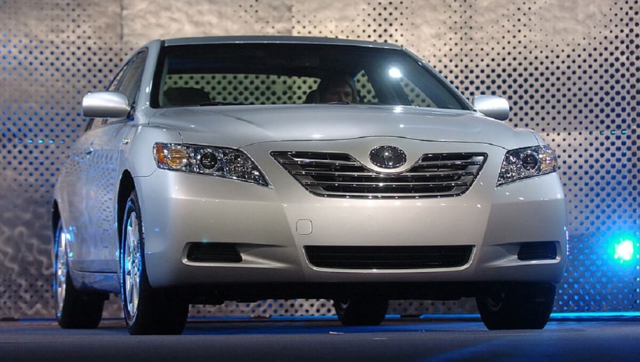 A used, silver 2007 Toyota Camry shows off its then-new car fascia under stage lights. 