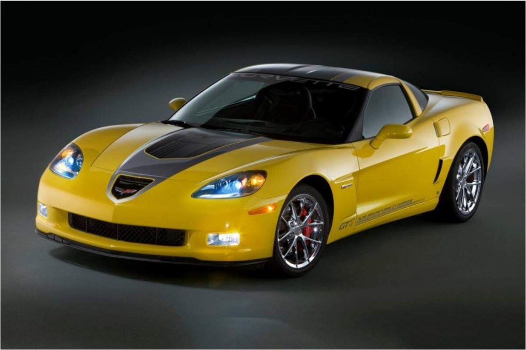 A yellow 2009 Chevrolet Corvette parked indoors in a black room with a black background. 