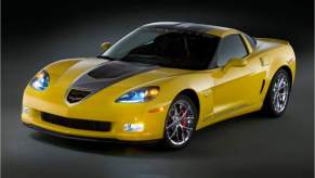 A yellow 2009 Chevrolet Corvette parked indoors in a black room with a black background.