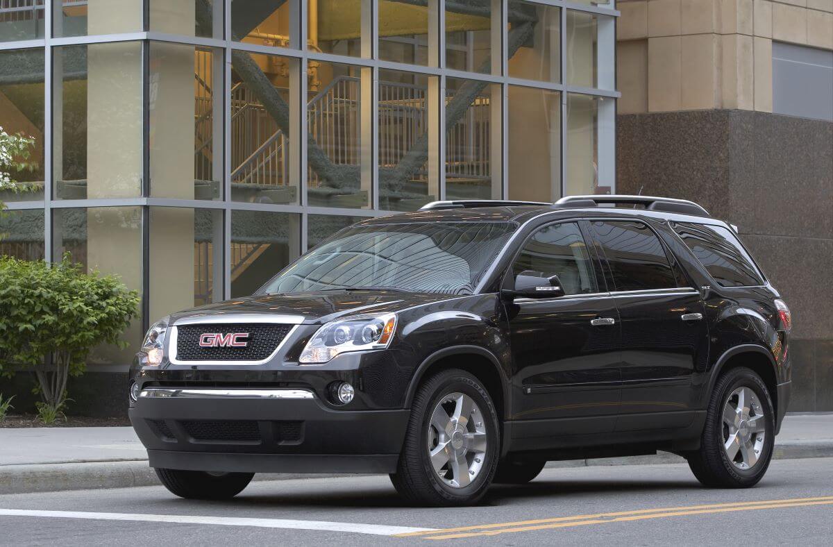 A black 2010 GMC Acadia midsize SUV model stopped at a light or stop sign