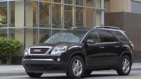 A black 2010 GMC Acadia midsize SUV model stopped at a light or stop sign
