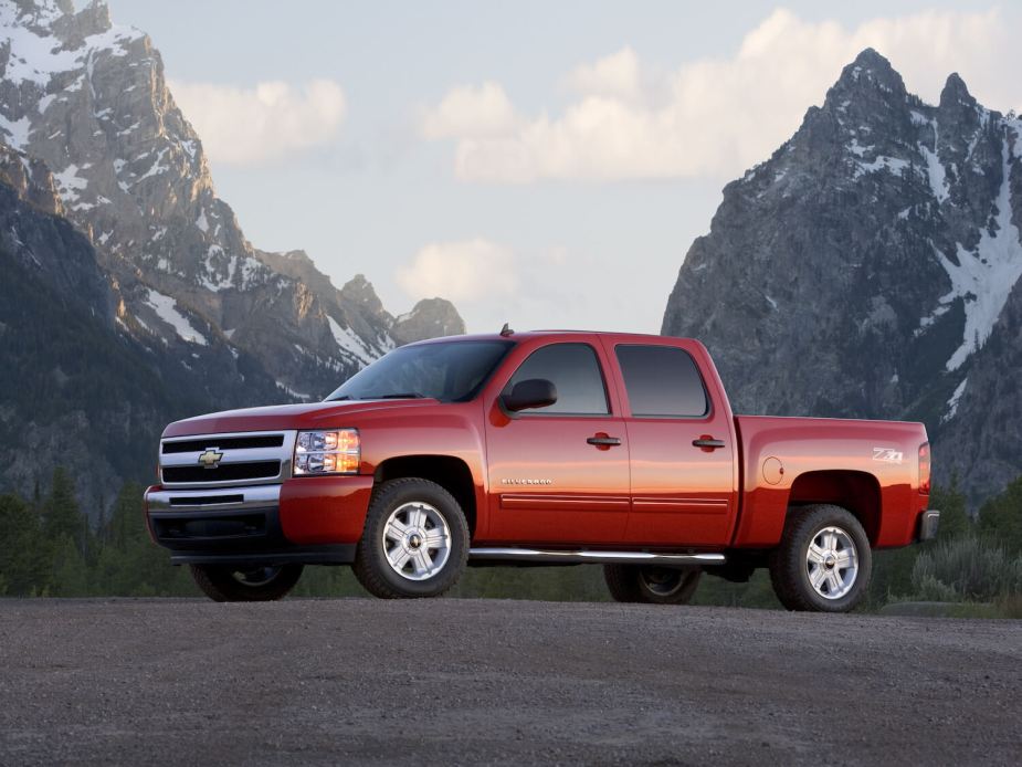 A red Chevrolet Silverado parked in front of mountains.