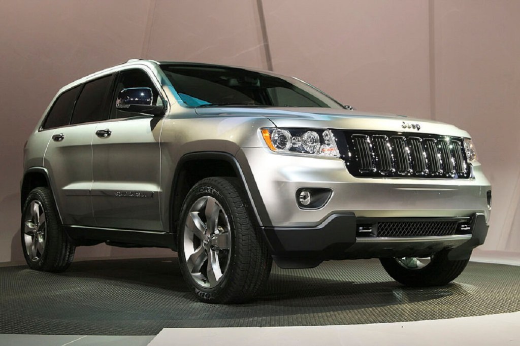 A silver 2011 Jeep Grand Cherokee poses on stage.