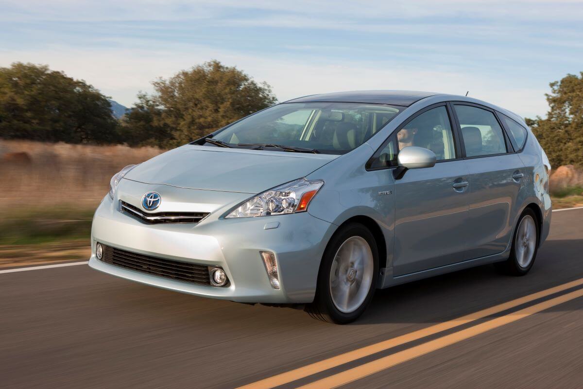 A light blue 2011 Toyota Prius v hybrid hatchback model driving down a country highway