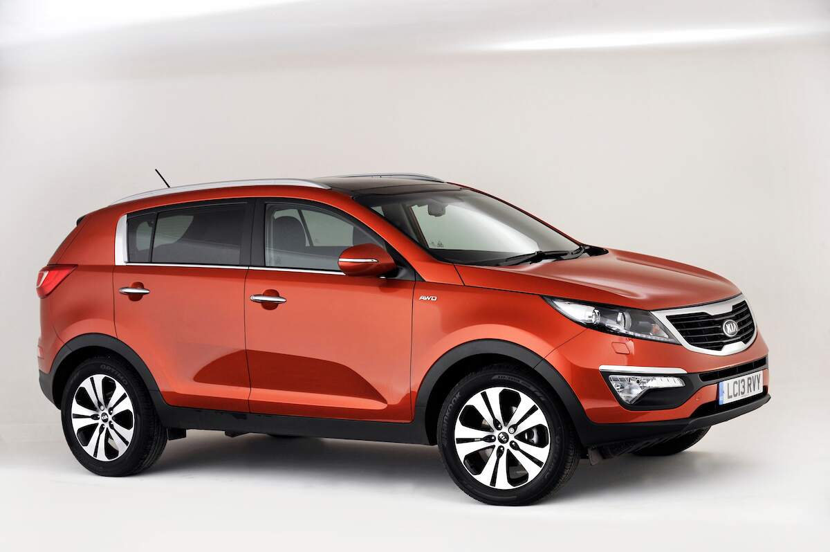 A red 2013 Kia Sportage parked in a white room. This is one of the worst Kia Sportage model years to buy