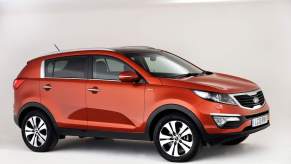 A red 2013 Kia Sportage parked in a white room. This is one of the worst Kia Sportage model years to buy