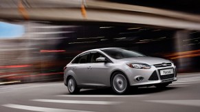 A silver 2014 Ford Focus models its front-end styling as it drives down a city street.