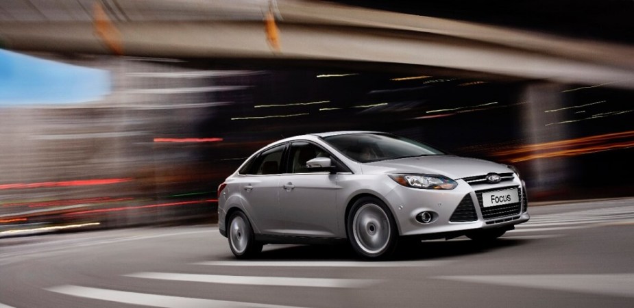 A silver 2014 Ford Focus models its front-end styling as it drives down a city street. 