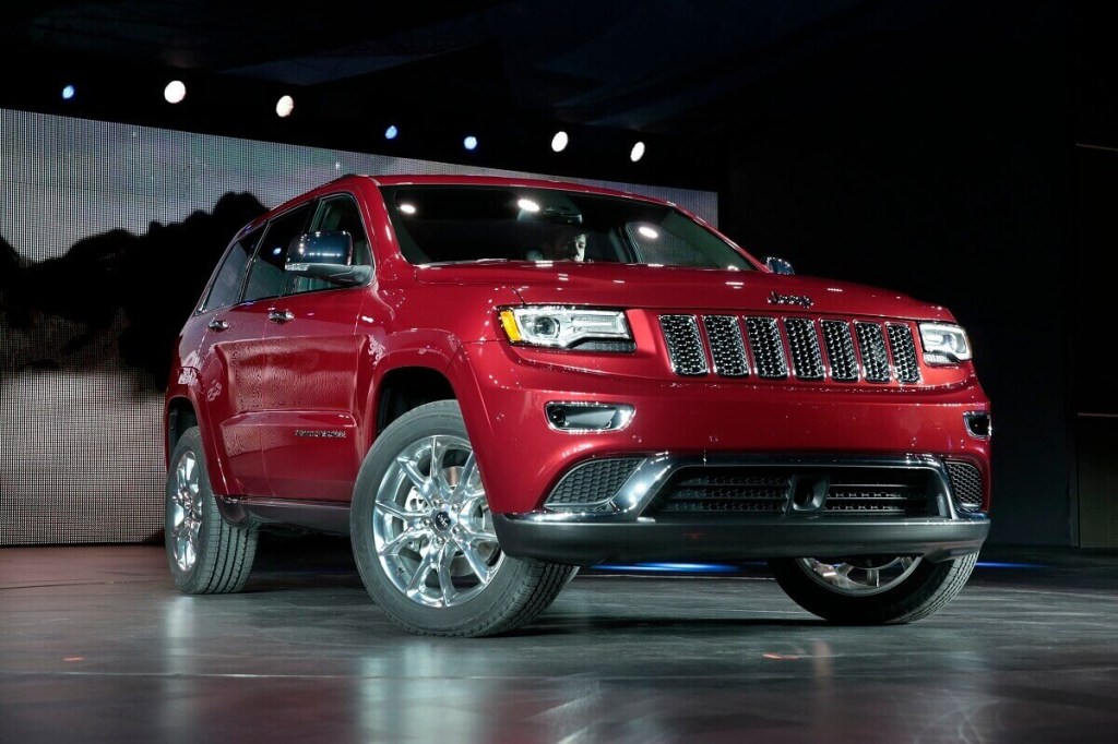 A 2014 Jeep Grand Cherokee shows off its red paintwork on a stage. 