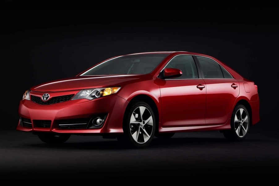 A red 2014 Toyota Camry poses against a dark backdrop.