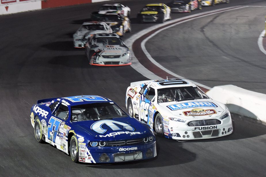 MOPAR branded Dodge race car on a NASCAR track, leading the pack.