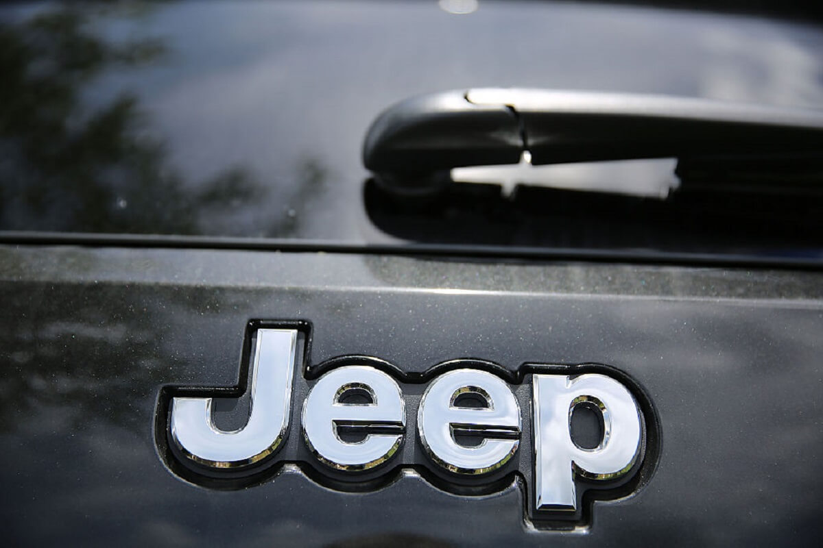 A 2014 Jeep Grand Cherokee model's badge on a car lot.
