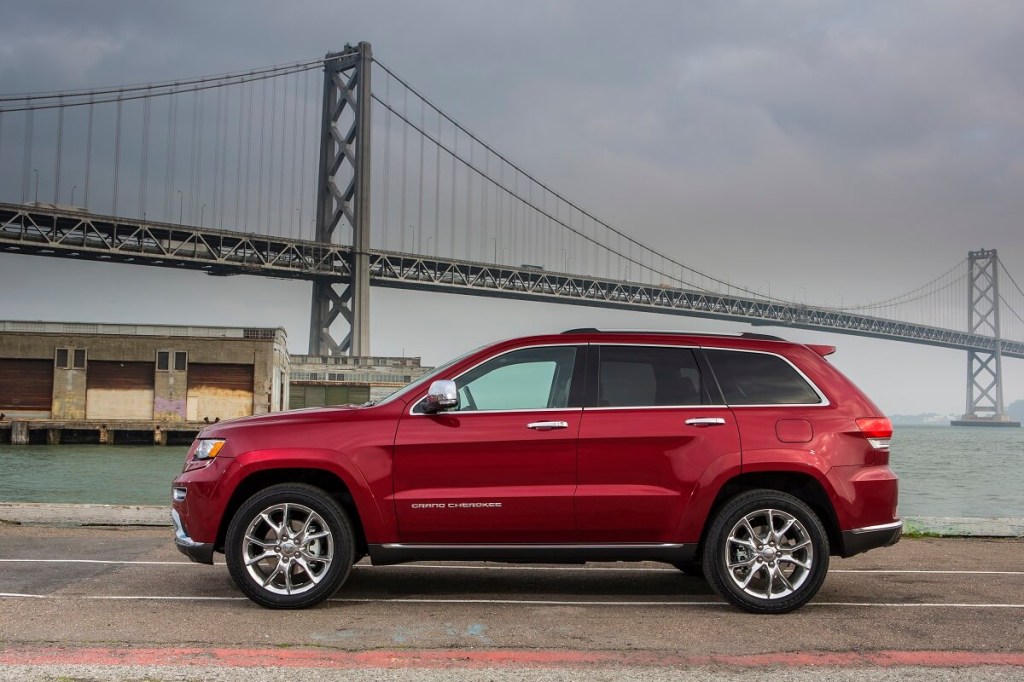 A red 2015 Jeep Grand Cherokee poses by the waterfront. 