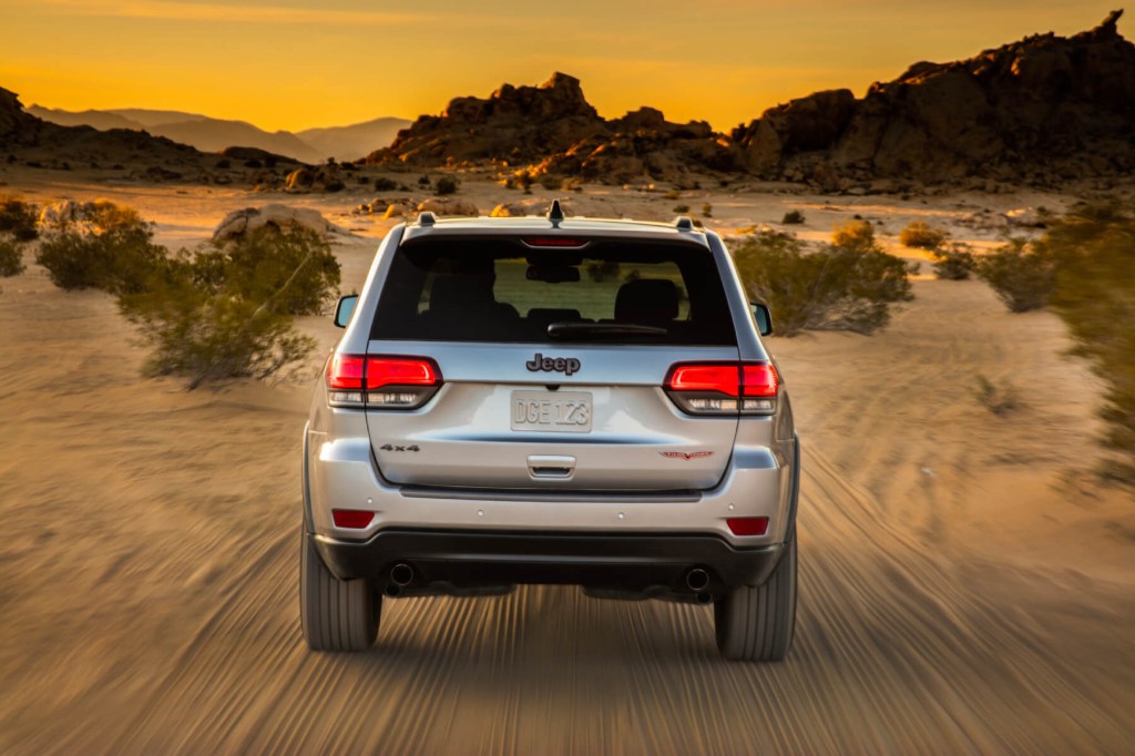 Rear view of a silver 2020 Grand Cherokee driving through the desert. Drivers must watch out for common used Grand Cherokee problems.