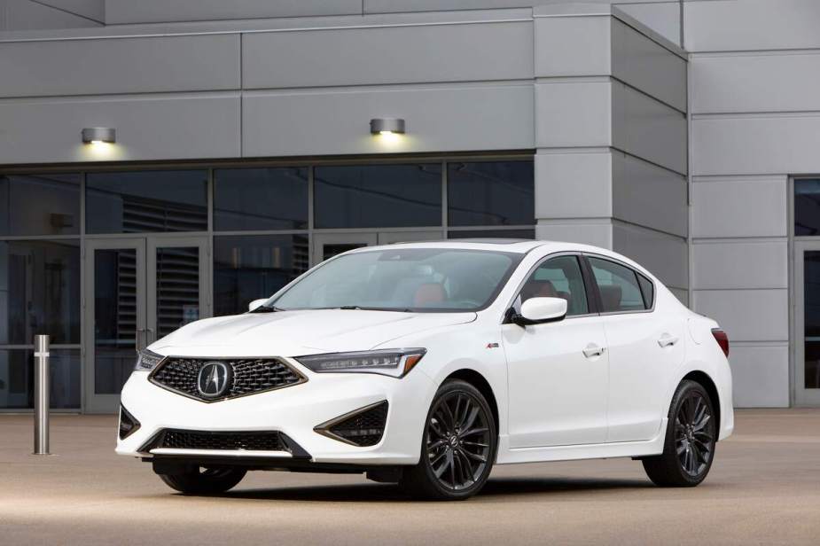 A white 2021 Acura ILX parked in front of a gray building.