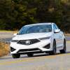 A white 2021 Acura ILX driving down a curvy road in a woody area.