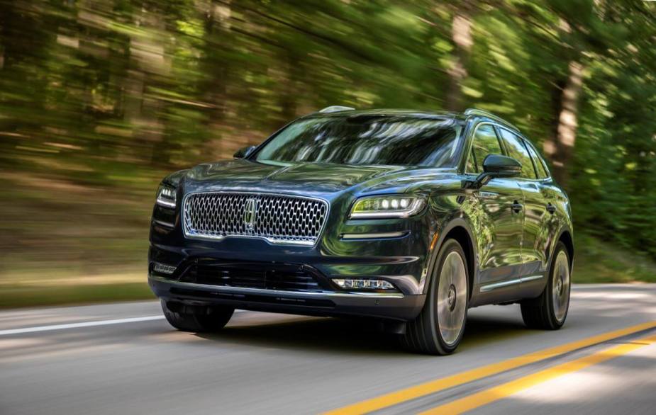 A 2021 Lincoln Nautilus Flight Blue midsize luxury SUV model driving on a forest highway