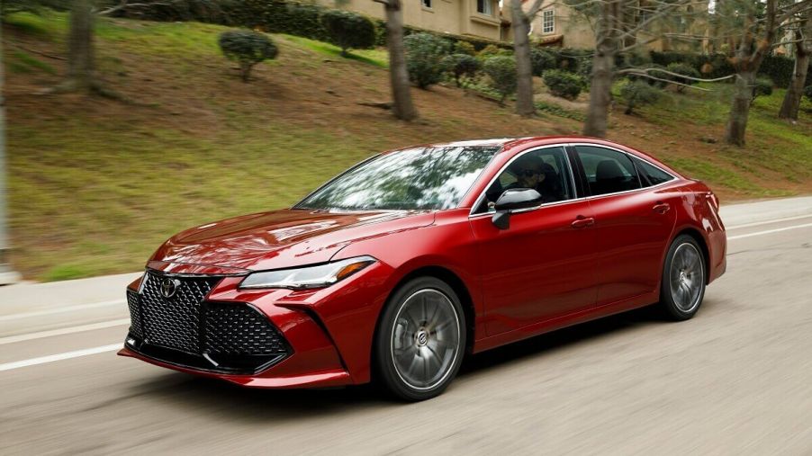 A red 2022 Toyota Avalon full-size car cruises down a country road.