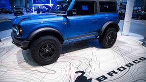 A blue two-door Bronco sits on the floor of an auto show.