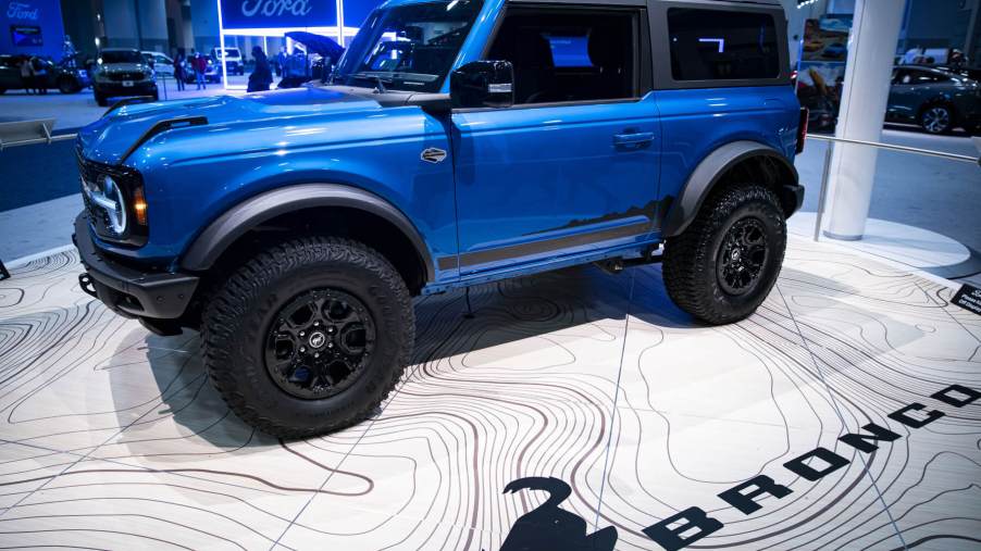 A blue two-door Bronco sits on the floor of an auto show.
