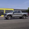 A gray 2023 Chevrolet Chevy Colorado Z71 midsize pickup truck model driving past a yellow building